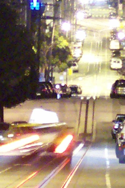 Streaks of light follow a taxi descending Washington Street at night toward San Francisco Chinatown